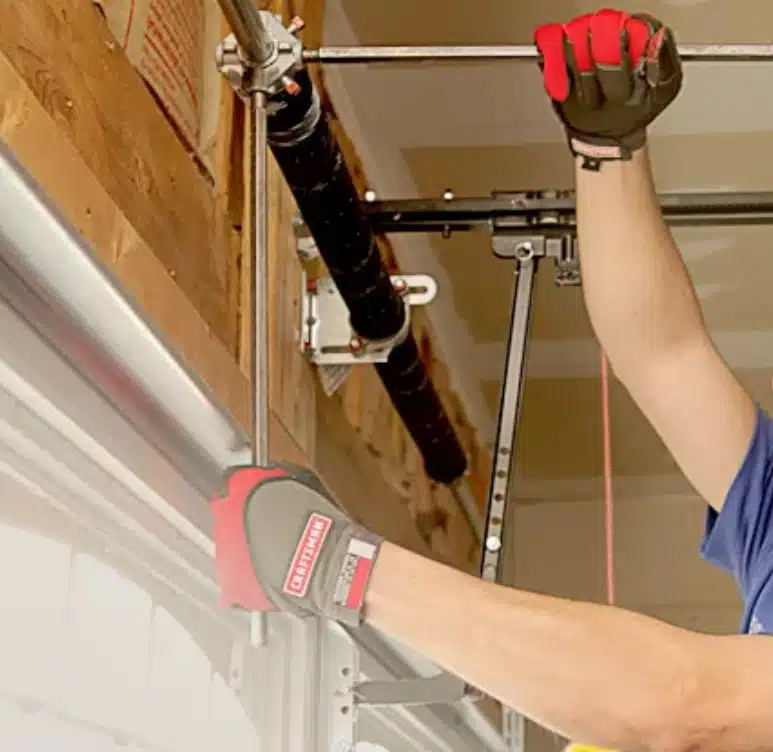 man's hands repairing broken spring on a garage door opener